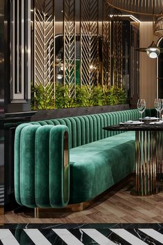 a green couch sitting next to a table in a room with black and white stripes on the floor