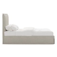 an upholstered bed with white sheets and pillows