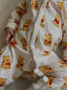 a baby is laying on the floor wearing winnie the pooh pajamas