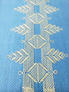 an intricate design on blue fabric with white thread and gold dots in the shape of a tree