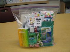 a plastic bag filled with toiletries on top of a wooden table next to a sign that says field trip kit