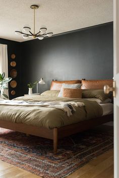 a bedroom with black walls and wooden furniture