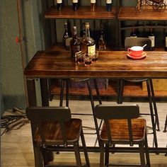 a wooden table topped with lots of bottles and chairs next to a shelf filled with wine bottles