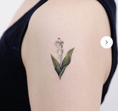 a woman's shoulder with a small flower tattoo on the left side of her arm