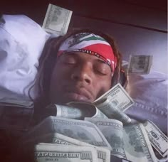 a man laying in bed with money wrapped around his head and bandana on top of his head