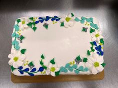 a white cake with blue and green flowers on it