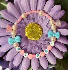 a purple flower with beads and bows around it's center surrounded by words that spell happy