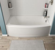 a white bath tub sitting inside of a bathroom next to a shower head and rug