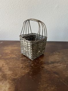 a metal basket sitting on top of a wooden table