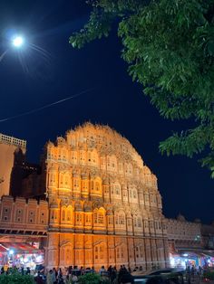 an ornate building lit up at night with people walking around