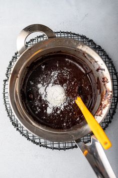 a pot with some food inside of it on a wire rack next to a yellow spatula