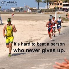 there are many people running on the beach and one person is holding his hand up