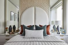 a bed with white headboard and pillows in a bedroom next to a large window