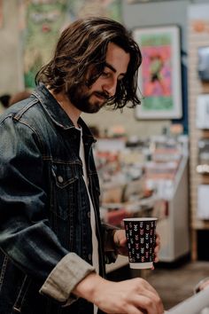 a man with long hair holding a coffee cup