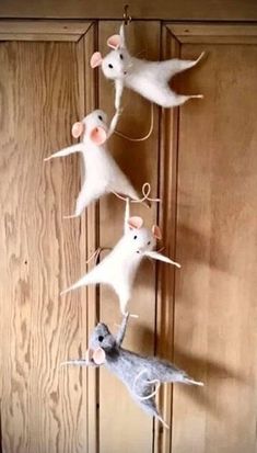 three white mice hanging from a door