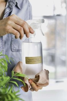 a person holding a spray bottle in front of a potted plant with a label on it