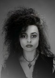 a black and white photo of a woman with long curly hair wearing a choker necklace