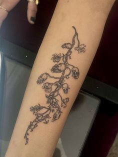 a woman's arm with a tattoo on it that has flowers growing out of it