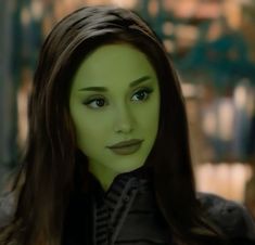 a close up of a person with green makeup and long brown hair wearing a black shirt