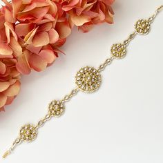 a close up of a bracelet on a white surface with flowers in the foreground