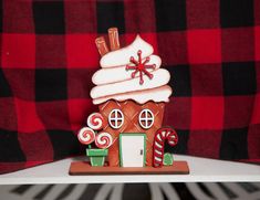 a gingerbread house decorated with icing and candy canes on a wooden stand