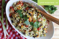 a white bowl filled with rice and vegetables on top of a red checkered table cloth