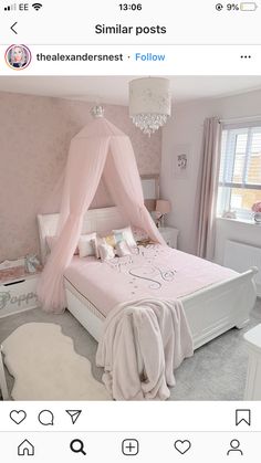 a bed with a pink canopy over it in a bedroom next to a chandelier