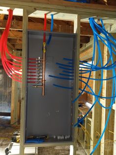 an electrical panel with blue and red wires connected to the back of it in a room under construction