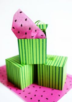 a watermelon slice sitting on top of a green box with pink tissue paper