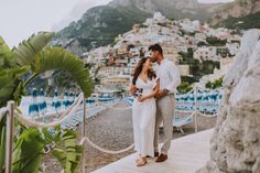 a man and woman standing on a dock next to the ocean