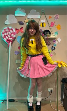 a woman in a yellow shirt and pink skirt standing next to a candy bar display