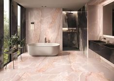 an elegant bathroom with marble walls and flooring, along with a freestanding bathtub