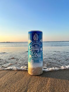 a can of beer sitting on top of a sandy beach