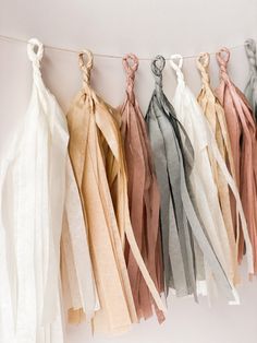 several different colors of tassels hanging from a line on a white wall,