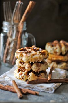 cinnamon roll cookies stacked on top of each other with cinnamon sticks in front of them