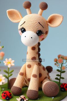 a crocheted giraffe sitting on top of a grass covered field with ladybugs