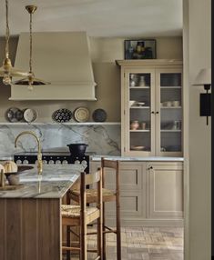 a kitchen with marble counter tops and wooden stools in front of an open cabinet