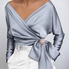 This 1940s top is at the height of Hollywood glam. Wide V-neck to envelop your cleavage and wrap subtly around the waist, creating the illusion of a beautifully draped torso. 

The satiny, stretchy fabric shines and makes this top a must-have for parties and evenings. Add a rhinestone brooch to elevate the top and pair it with one of our high waisted pencil skirts. 
Material: Polyester, Spandex
Details: V-neck wrap top, Bow at the waist, Long sleeves, Available in Plus Size, Brooch not included! Satin T Shirt, Rock Outfit, Retro Mode, Women Tunic Tops, Satin Shirt, Moda Vintage, Satin Blouse, Satin Top, Elegant Shirt