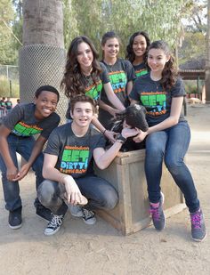 a group of young people posing for a photo with a small animal in a crate