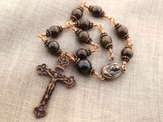 Handmade one decade Catholic rosary beads with Our Lady with Child medal and Eucharistic crucifix. Single decade pocket rosary is made in unbreakable wire wrapped technique with 8mm natural bronzite and 10mm natural astrophyllite gemastone beads and antique copper medal and crucifix. All of the materials used in making rosaries are hand picked and undergo utmost quality check. Packaged in a gift box. Rosary's length is about 8" (21 cm) Crucifix: 1.1"x 1.8" (2.8 x 4.5 cm) See more one decade rosa Making Rosaries, One Decade Rosary, Pocket Rosary, Rosary Beads Catholic, Decade Rosary, Catholic Rosary, Rosary Catholic, Rosary Beads, Our Lady