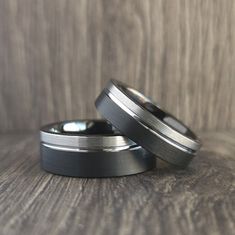 two wedding bands are sitting on top of each other in front of a wooden background