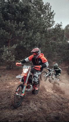 two people riding dirt bikes on a trail