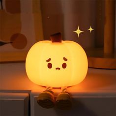 a glowing pumpkin sitting on top of a white counter next to a window with stars in the background