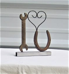 a metal hook with a heart and a wrench on it sitting on top of a table