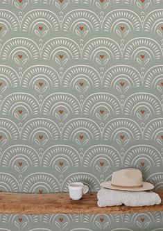 a hat and cup on a wooden table in front of a wallpapered background