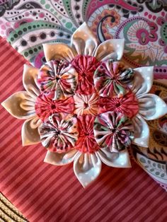 a close up of a flower on top of a red and white table cloth with paisley designs