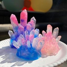 two small pieces of ice on a white paper plate with blue and pink icing