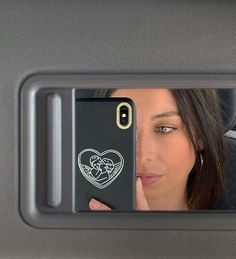 a woman looking at her phone in the back seat of a car with a heart sticker on it