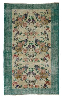 an antique rug with flowers and leaves on green ground, in front of a white background