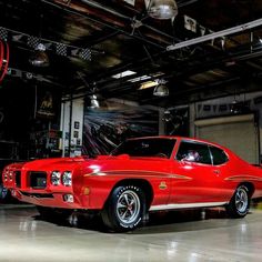 a red muscle car parked in a garage